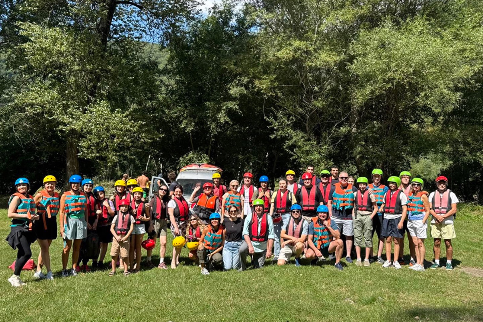 A group in life jackets and helmets before a raft trip